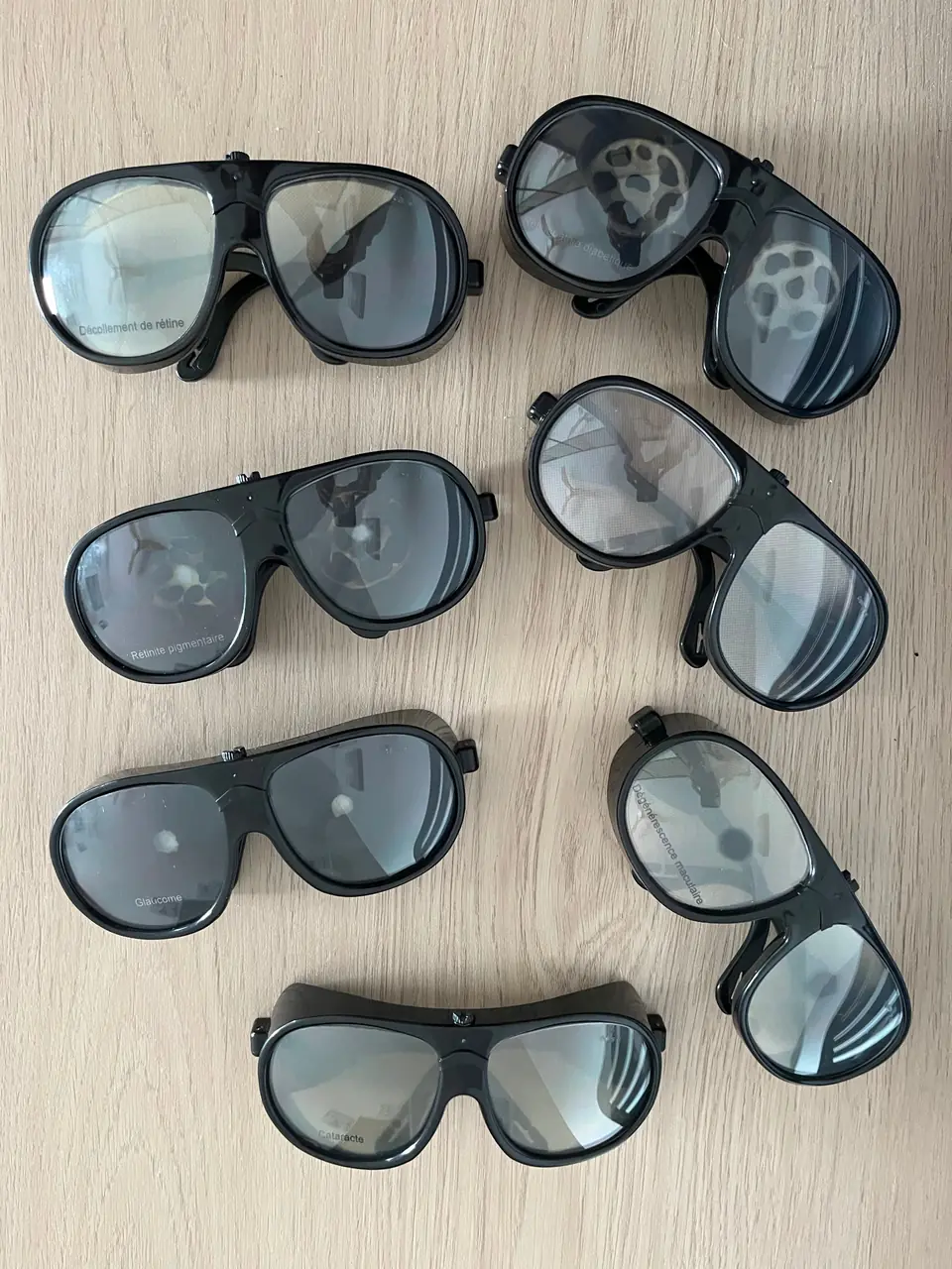 Lunettes de simulation de troubles visuels posées sur une table : cataracte, glaucome, dégénérescence maculaire, rétinopathie diabétique, rétinite pigmentaire, décollement de rétine